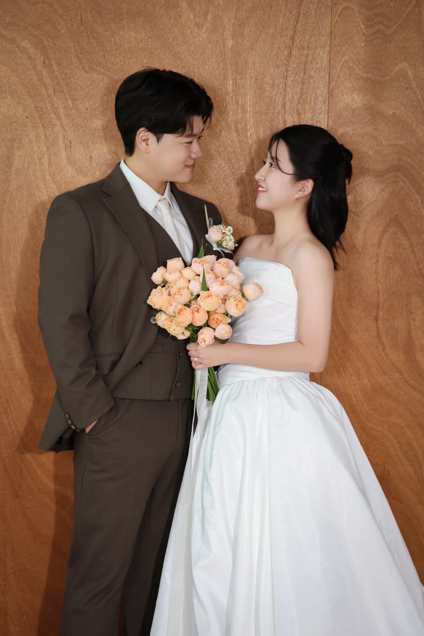 우드 배경 앞에서 서로를 바라보는 신랑 신부